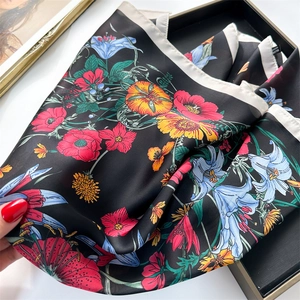 Detail of floral print silk scarf featuring vivid lilies and high-gloss satin texture