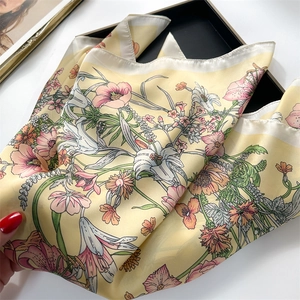 Detailed view of yellow floral silk scarf draped elegantly over a black tray