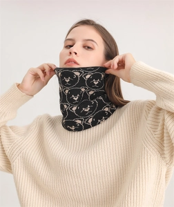 Detailed view of black knitted neck gaiter with beige bear pattern on a model