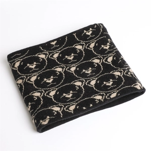 Detail shot of black knitted neck warmer with thick cream bear jacquard pattern