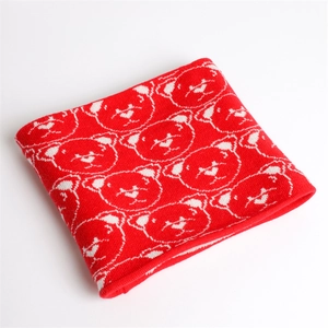 Detail of red knitted neck warmer featuring white bear patterns and soft texture