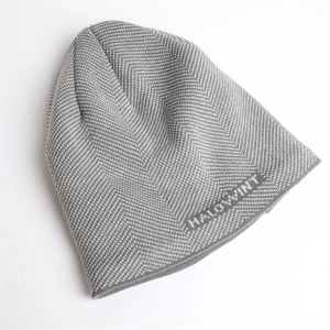 Macro detail of gray knitted beanie with herringbone pattern and HALOWINT text embroidery