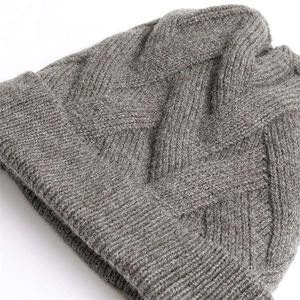 Nahaufnahme der grauen Strickmütze mit Zopfmuster, dickem Rippstrick und warmen Texturen