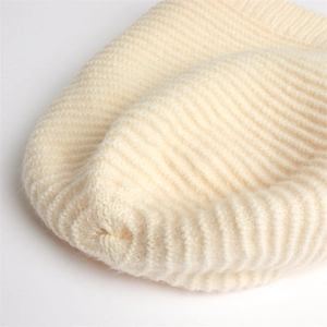 Close-up of the rib-knit stitching and professional seam finish on the cream beanie top