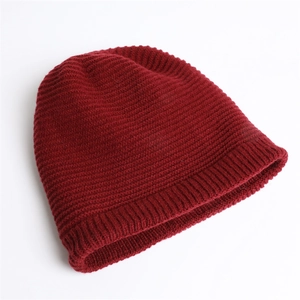 Close-up of wine red knitted beanie showing thick ribbed texture and warm folded cuff