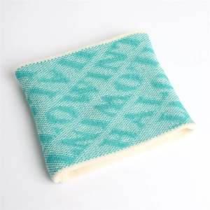 Detail of teal and cream jacquard knit neck warmer with geometric pattern texture