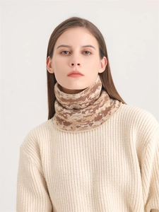 Détail de la maille du cache-cou camouflage marron porté avec un pull en tricot blanc doux