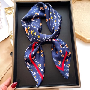 Detail of floral silk scarf in navy blue and red border inside a gift box presentation