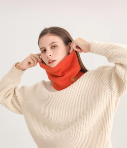 Détail d'un tour de cou en tricot orange vif avec étiquette cuir et texture côtelée