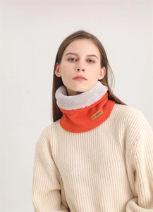 Détail d'un tour de cou en tricot orange avec doublure polaire grise et patch en cuir