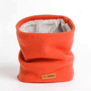 Détail d'un tour de cou tricoté orange avec doublure polaire grise et écusson en cuir