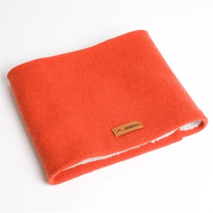 Détail du cache-col en tricot orange avec doublure polaire blanche et écusson logo en cuir