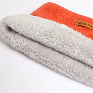 Gros plan du tour de cou en tricot orange avec doublure polaire grise et écusson cuir