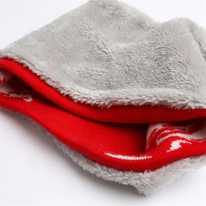 Dettaglio della sciarpa in maglia rossa con fodera in peluche grigia e motivi a fiocchi