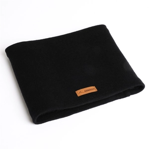 Détail de la maille du cache-cou noir avec écusson en cuir marron et logo embossé