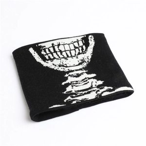 Dettaglio dello scaldacollo in maglia nera con motivo jacquard di teschio bianco e colonna