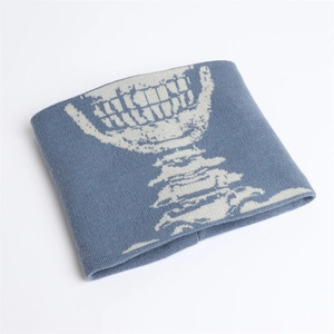 Dettaglio dello scaldacollo in maglia blu spessa con stampa a teschio bianco