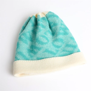 Detail of teal and cream winter knit hat showing geometric jacquard texture and thick cuff