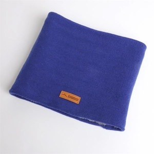 Gros plan du cache-col en tricot bleu avec doublure polaire grise et étiquette en cuir