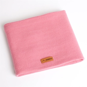 Détail du cache-col en tricot rose avec texture fine et étiquette de marque en cuir brun