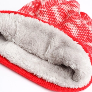 Detailed close-up of thick red knit pattern and warm grey faux fur lining of the winter hat