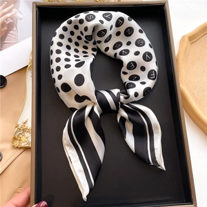 Detailed close-up of polka dot and stripe silk scarf folded in a luxury gift box