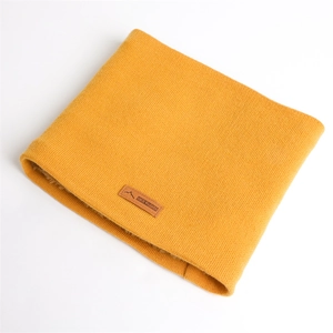 Détail du cache-col en tricot jaune avec doublure polaire et écusson en cuir
