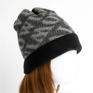 Detail of a warm winter beanie featuring a black and grey knit wave pattern and cuffed brim