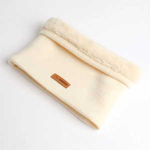 Détail du cache-col en tricot ivoire avec doublure pelucheuse blanche et logo en cuir