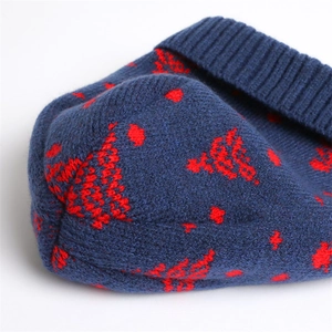 Detail view of navy blue knit beanie featuring red snowflake patterns and ribbed cuff texture