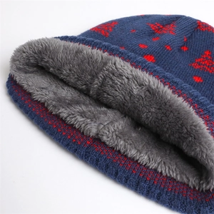 Close-up of winter knit hat showing thick grey faux fur lining and Christmas tree pattern