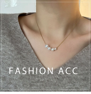 Detail of five graduated faux pearls on a fine gold chain worn by a model