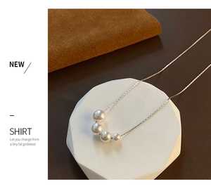 Detail shot of white faux pearl necklace with gradient sizes on a silver-tone chain