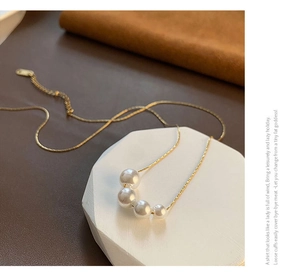 Detailed macro shot of four graduated faux pearls on a gold chain over geometric stone