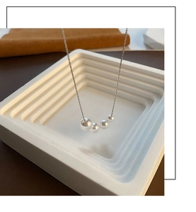 Macro view of polished silver bead pendant necklace on minimalist geometric display