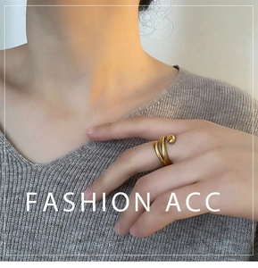 Detail of a minimalist gold wrap ring with polished metal ball ornament on finger