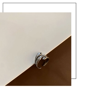 Detail of silver fluid ring with three parallel metallic lines and a polished finish