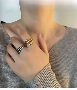 Detail shot of fluid wave design rings in gold and silver finish on model's fingers