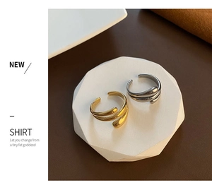 Detailed view of wrap-around titanium steel rings in gold and silver on a white stand