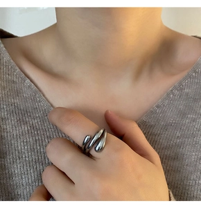 Detail of silver liquid metal ring with fluid lava design worn on index finger