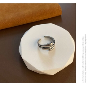 Macro view of a silver hug-style titanium ring with a liquid-drop wrap design on a tray