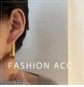 Close-up of minimalist gold U-shaped drop earrings worn by a model in natural light