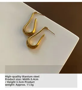 Macro shot of gold U-shaped titanium earrings showing 0.4cm width and 3.5cm height dimensions