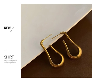 Macro shot of minimalist 18K gold-plated U-shaped earrings with a polished mirror finish