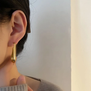 Minimalist matte gold teardrop earring with modern liquid metal design on model