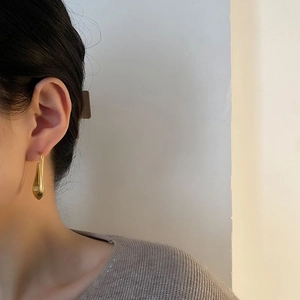 French style minimalist gold teardrop earrings for women worn by a model in soft light
