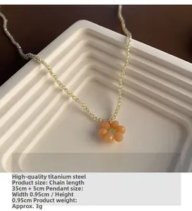 Gros plan du pendentif fleur pêche avec sa chaîne perlée en acier titane de haute qualité