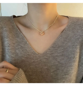 Détail du collier ras de cou perlé avec un délicat pendentif fleur rose sur un mannequin