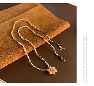 Détail macro du collier de perles avec pendentif fleur coloré et fermoir mousqueton doré