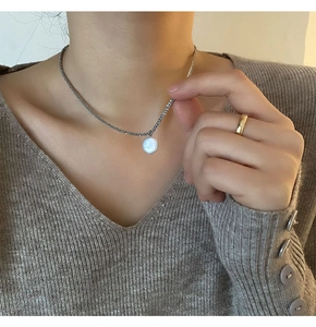 Elegante close-up van een witte barokke parelketting gedragen op een grijze V-hals trui